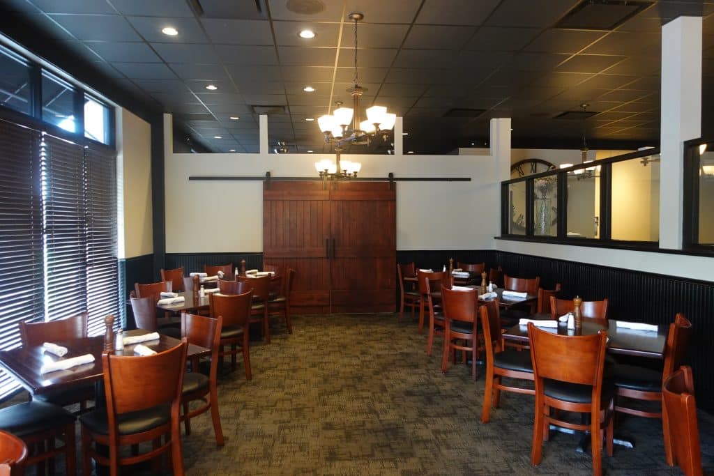 A beautifully painted restaurant interior in Wichita, KS, featuring warm wooden furniture, stylish lighting fixtures, and a professional finish. Roll Call Painting specializes in commercial interior painting to create inviting spaces for businesses.