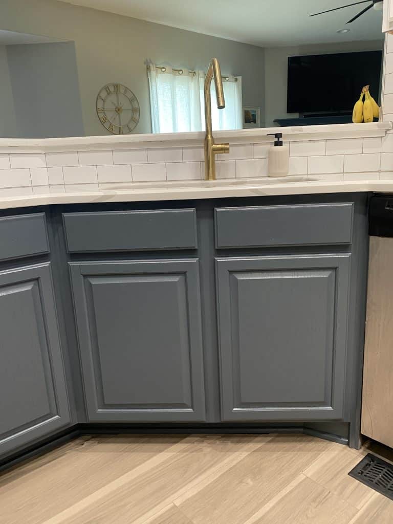 A fully refinished kitchen in Wichita, KS, featuring two-tone cabinetry with satin white upper cabinets and matte black lower cabinets. The sleek design includes quartz countertops, modern pendant lighting, and stainless steel appliances, showcasing expert cabinet refinishing craftsmanship.