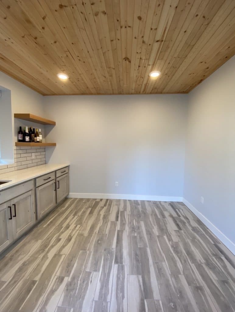 A newly painted commercial space in Wichita, KS, featuring custom-painted cabinets, a natural wood ceiling, and floating shelves. The modern design creates a clean and inviting work environment.
