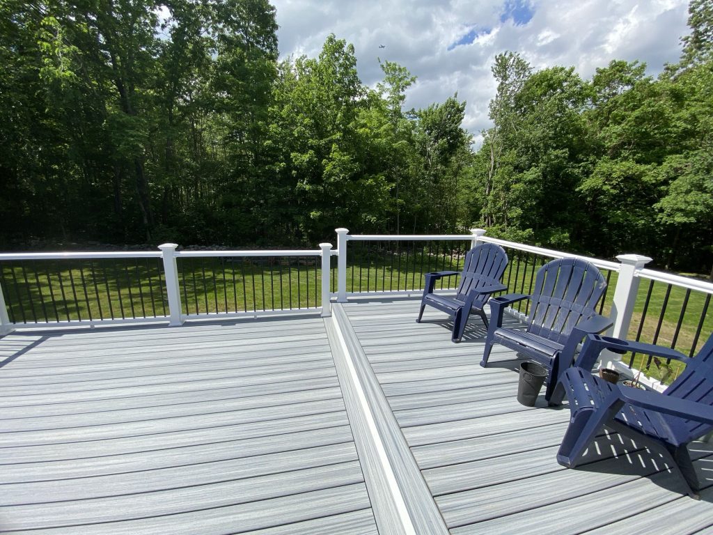 Spacious deck with chairs overlooking lush green backyard.