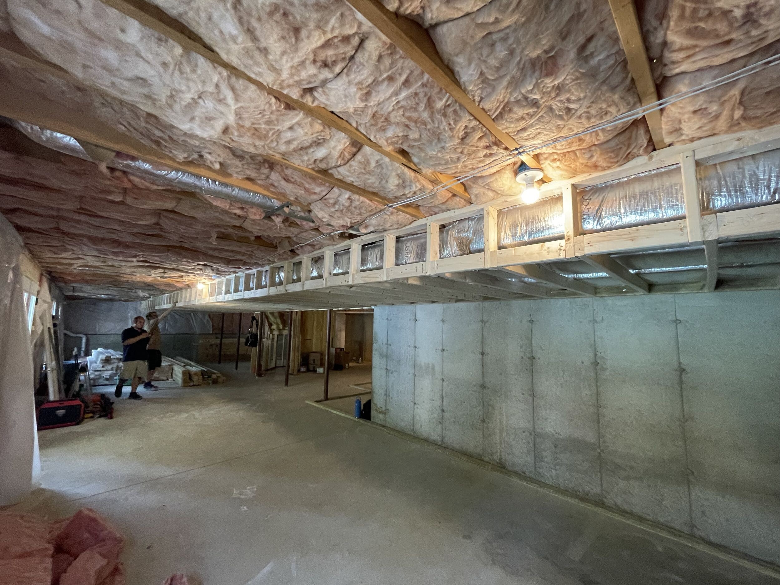 Insulated unfinished basement under construction with wood framing.