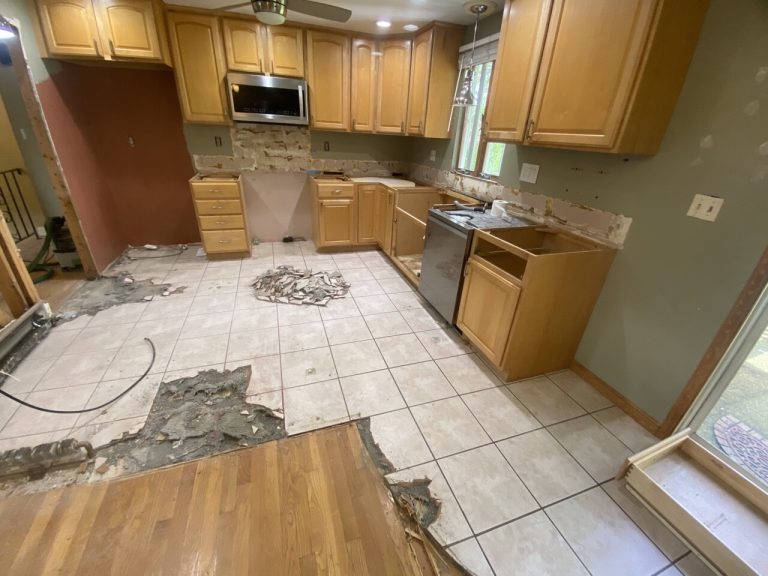 Kitchen renovation with removed cabinets and damaged floor.