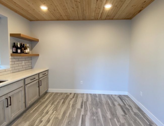 A newly painted commercial space in Wichita, KS, featuring custom-painted cabinets, a natural wood ceiling, and floating shelves. The modern design creates a clean and inviting work environment.